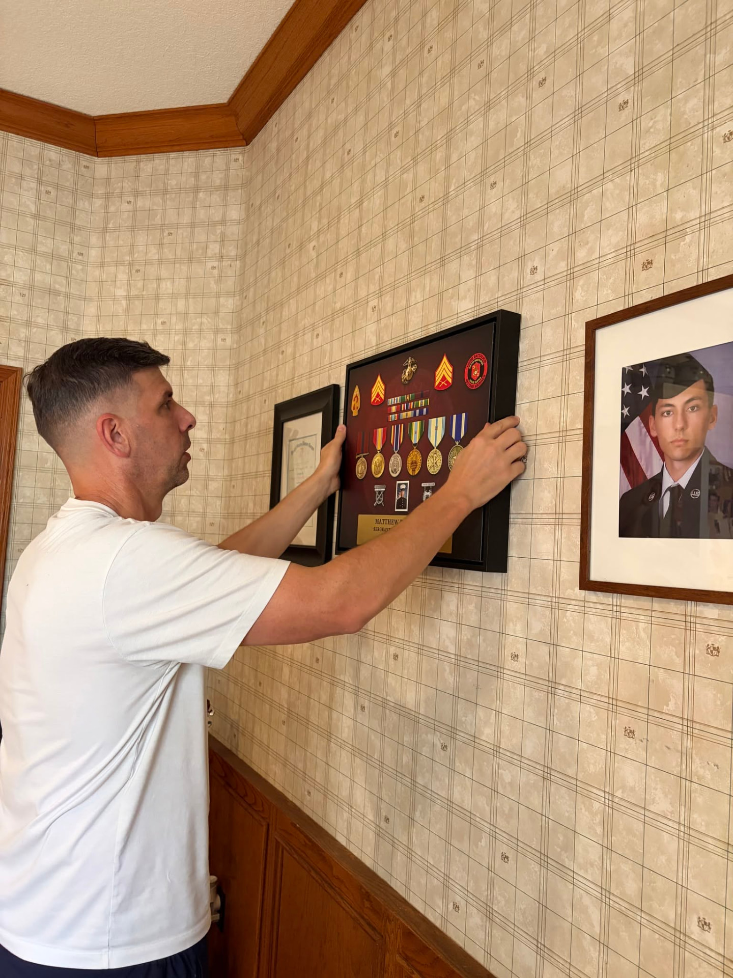 Matt Menster hanging his framed Valor Canvas on a hallway wall